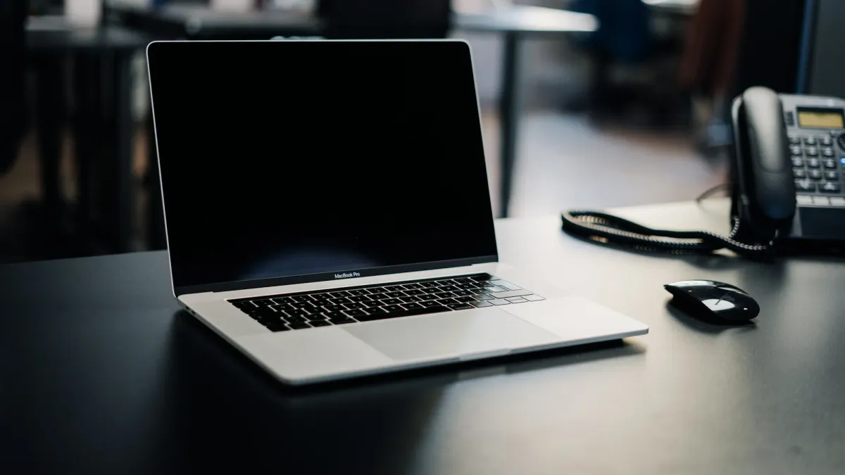Open laptop beside a desk phone and headset in a quiet office