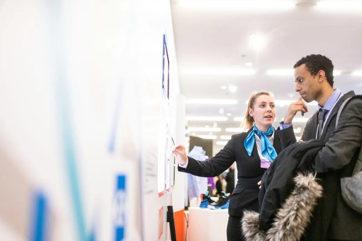 Two professionals reviewing information at a conference, a start in entry-level crypto jobs