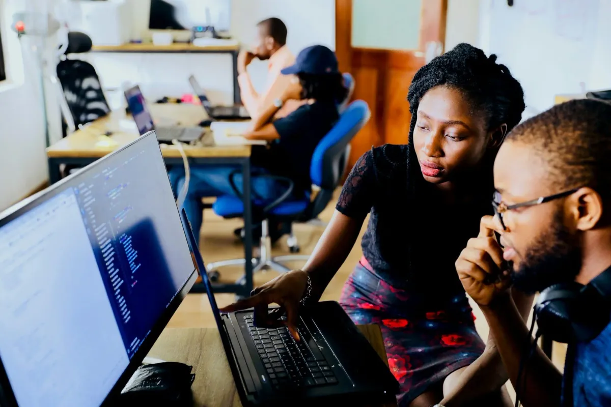 Two colleagues collaborating at a monitor, making the move from web2 to web3