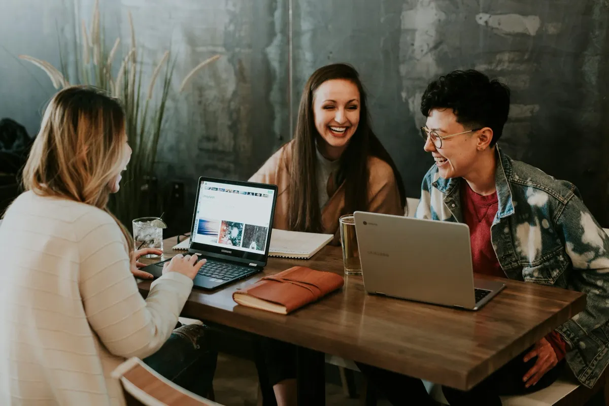 Three people studying together with laptops at a table