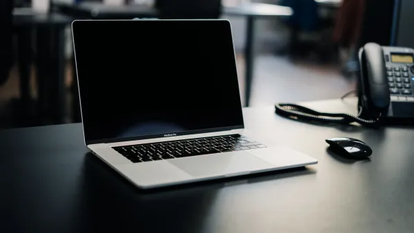 Open laptop beside a desk phone and headset in a quiet office