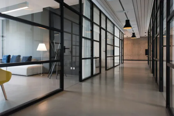 Empty modern office corridor with glass partitions and the lights still on
