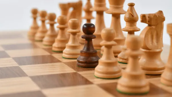 Wooden chess pieces facing off across a chessboard