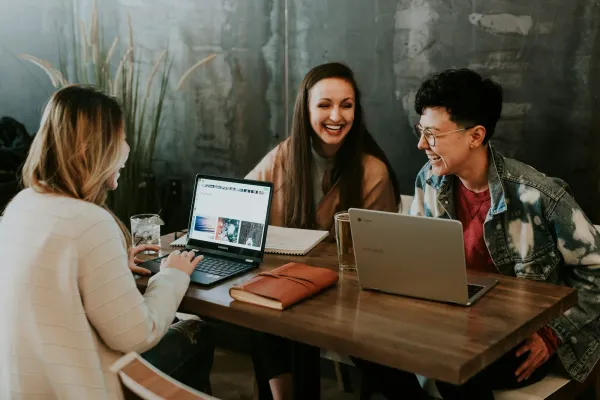 Three teammates talking and laughing, the people work of a web3 community manager