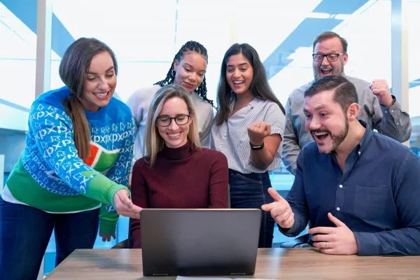 A creative team gathered around a laptop, the work of web3 marketing jobs