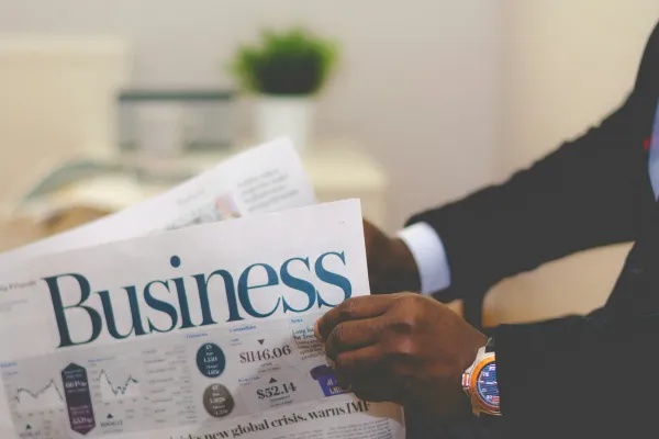 Person in a suit holding a pink business newspaper