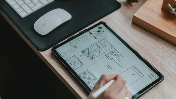 Hand sketching app wireframes on a tablet at a wooden desk